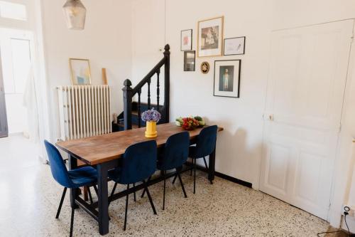 una mesa de comedor con sillas azules y una escalera en Maison avec jacuzzi, 
