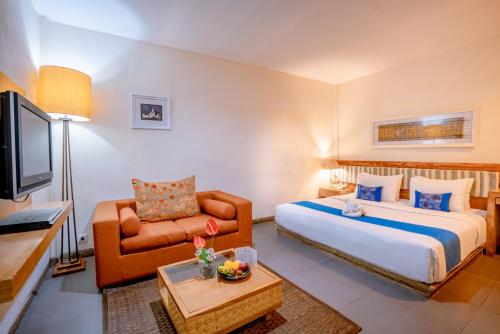 a bedroom with a bed and a couch and a tv at Pondok Sari Kuta in Kuta