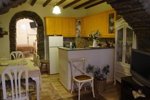 cocina con armarios amarillos, mesa, mesa y sillas en Το Σπίτι του Παππού, en Stení