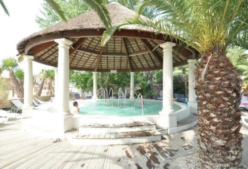 a swimming pool with a umbrella and a palm tree at Agde MOBIL HOME 3CH-SECTEUR VIP GARDEN VILLAGE CLUB PARC ACQUATIQUE in Le Grau-dʼAgde