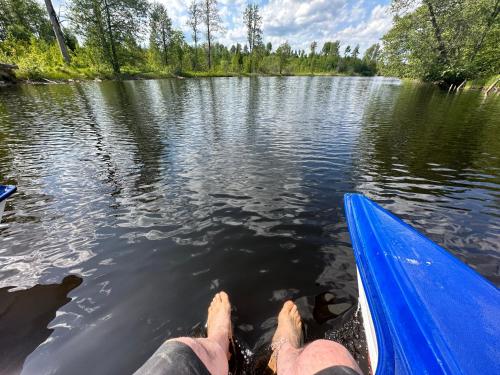 a man laying on the back of a boat in the water at Sjöutsikt, Röd trästuga med traditionellt yttre Skandinavisk, modernt inre och alla bekvämligheter, Sol hela dagen på stora altanen, Tryggt, Vinterbonat, Fiske, Båt in Skinnskatteberg