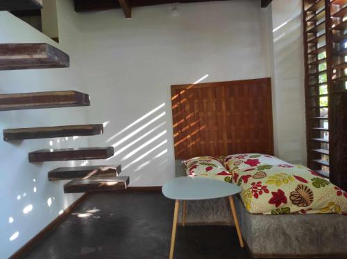 a bedroom with a bed and a table and stairs at Moemoea Lodge in Ambatoloaka