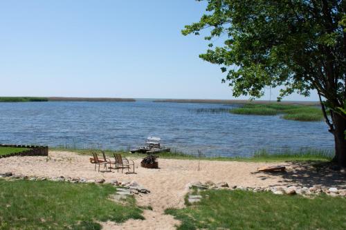 een strand met stoelen en een boot in het water bij Cozy Home Lake Huron II in Au Gres