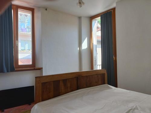 a bedroom with a bed and two windows at La Capinera in Muggio