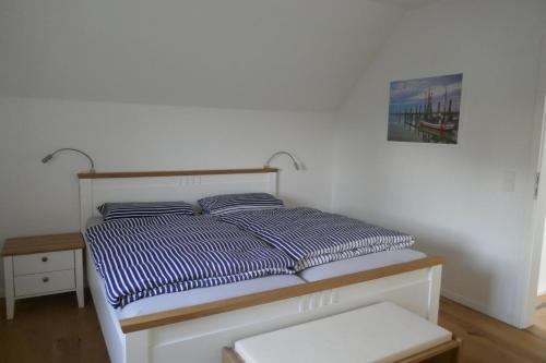 a bed with blue and white striped pillows in a bedroom at Stüürmanns Huus in Hilgenriedersiel