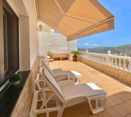 - un balcon avec des chaises et un grand parasol dans l'établissement CASA ROSALÍA. APARTAMENTO CON VISTAS A LA MONTAÑA, à Teror