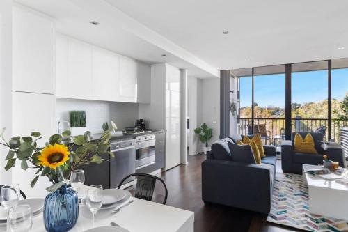a kitchen and living room with a table with a vase with a sunflower at Urban Uptown: Stylish Richmond in Melbourne