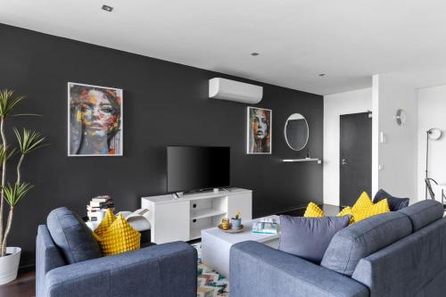 een woonkamer met twee blauwe banken en een tv bij Urban Uptown: Stylish Richmond in Melbourne
