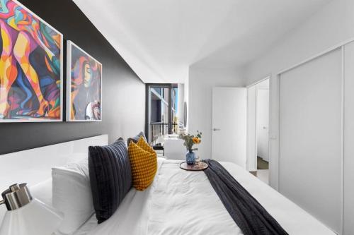 a bedroom with a large white bed with yellow pillows at Urban Uptown: Stylish Richmond in Melbourne