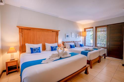 a bedroom with three beds with blue and white at Pondok Sari Kuta in Kuta
