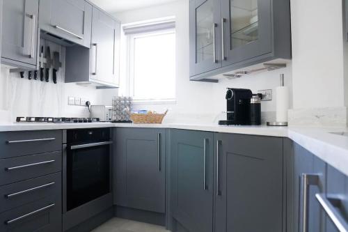 a kitchen with white cabinets and a black dishwasher at Stunning modern space with harbour views & free parking in Brighton & Hove