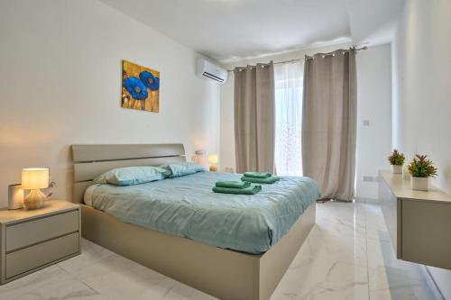 a bedroom with a bed with two green towels on it at The Hill 245 Modern Apt: 10 Minutes from the Beach in Taʼ Ċikkun