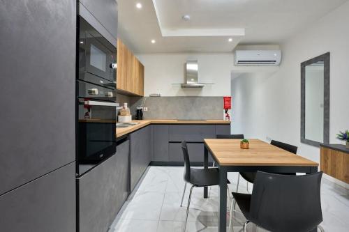 a kitchen with a wooden table and black appliances at The Hill 245 Modern Apt: 10 Minutes from the Beach in Taʼ Ċikkun