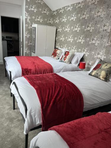 a bedroom with two beds with red and white blankets at Moorside House in Bolton