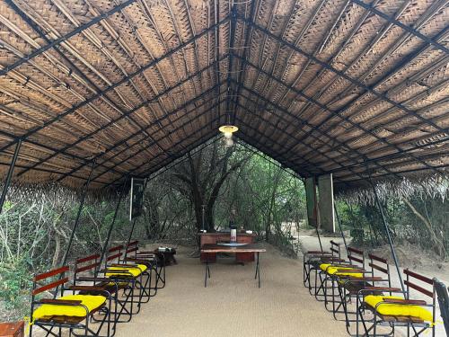 a pavilion with chairs and a table and a piano at Mahoora Wilpattu - by Eco Team in Wilpattu