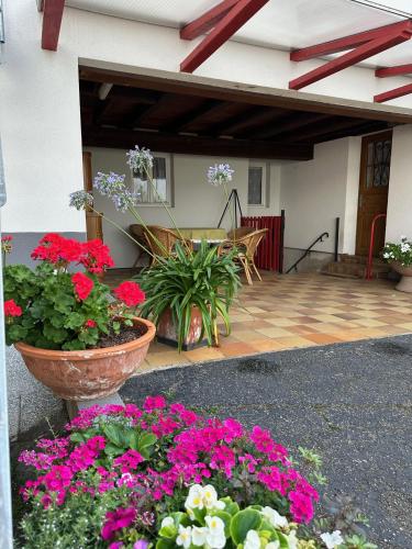 a patio with flowers in front of a house at Au parfum des roses in Gunstett