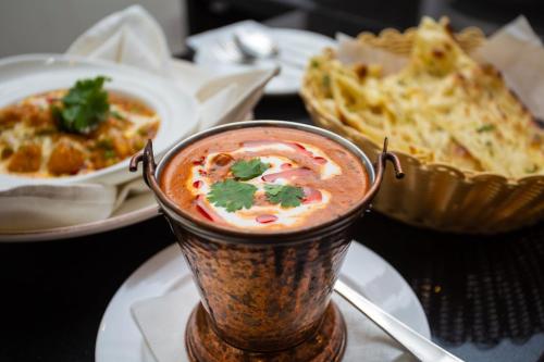 a cup of soup on a table with a plate of food at Pashupati Boutique Hotel & Spa in Kathmandu