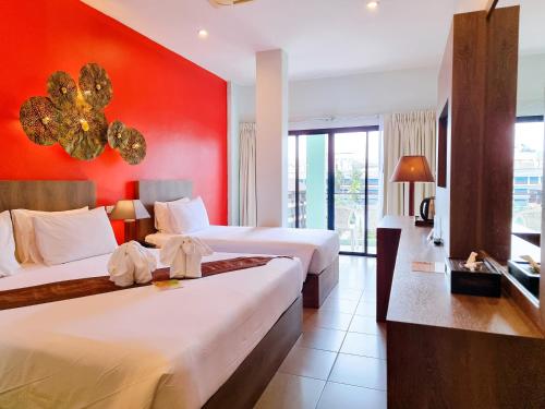 Habitación de hotel con 2 camas y pared roja en Meir Jarr Hotel Patong, en Patong Beach