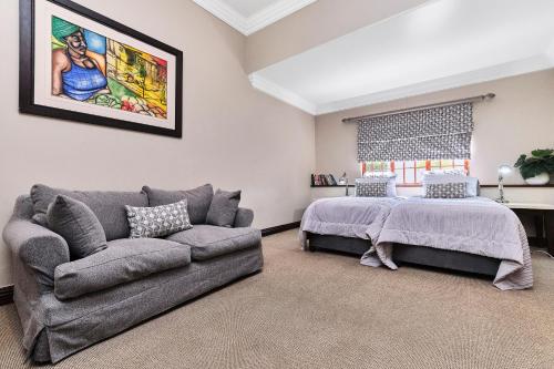 a living room with a bed and a couch at Rose Road Manor - Houghton Johannesburg in Johannesburg