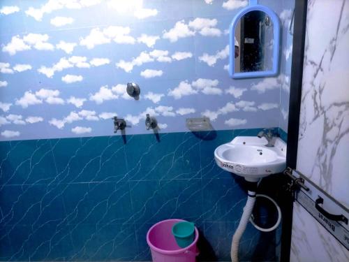 a bathroom with a sink and clouds on the wall at HOTEL SAMRAT PALACE in Ayodhya