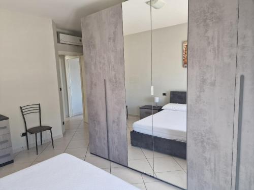 1 dormitorio con espejo, 1 cama y 1 silla en Residenza Adriatica 4, en Roseto degli Abruzzi