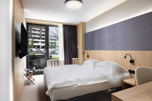a hotel room with a bed and a desk and a window at Hotel Kompas in Bled