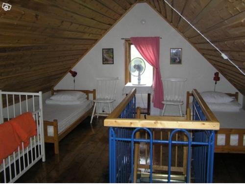 a attic room with two beds and a window at Sydöstra Gotland in Hemse