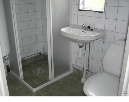 La salle de bains blanche est pourvue d'un lavabo et de toilettes. dans l'établissement Sydöstra Gotland, à Hemse