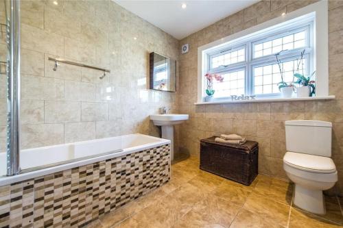a bathroom with a tub and a toilet and a sink at 3 bedroom house, 5 mins to the station, Super-wifi , Longer stays available in Kent