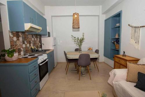 a kitchen with blue cabinets and a table and a couch at Ammoudara Apartment's in Kalymnos