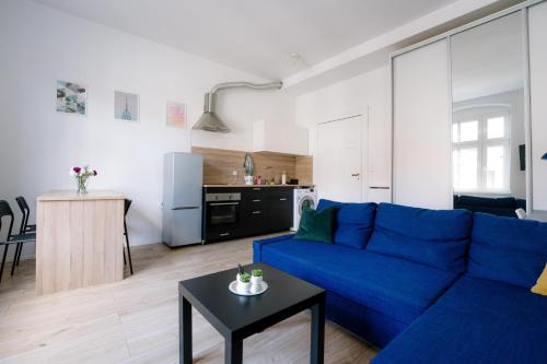 een woonkamer met een blauwe bank en een keuken bij Restful Stay Apartment in Grudziądz