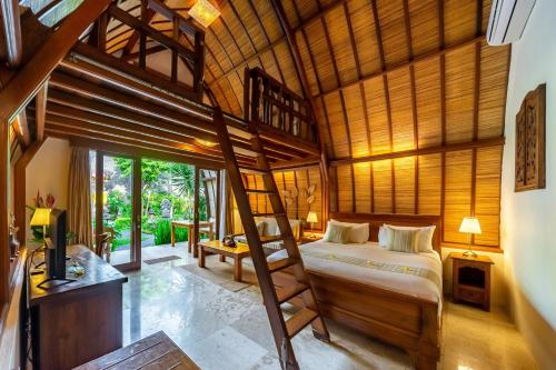 a bedroom with a bed in a room with wooden ceilings at Klumpu Bali Resort in Sanur