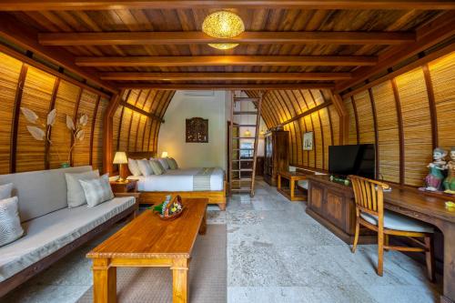 サヌールにあるKlumpu Bali Resortのソファ、ベッド、テレビが備わる客室です。