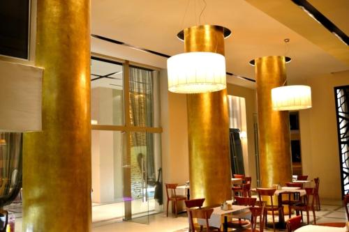a restaurant with tables and chairs and gold columns at Evridiki in Kilkís