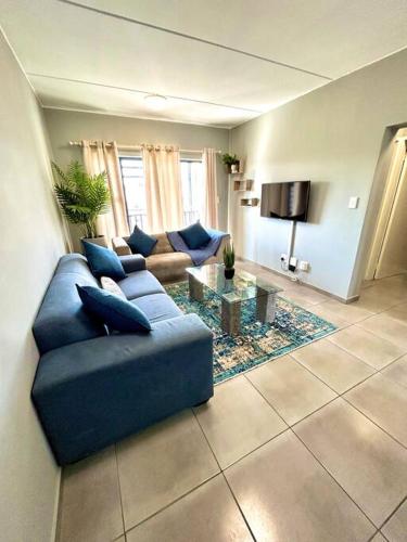 a living room with a blue couch and a table at The Place @ Mall of Africa in Midrand