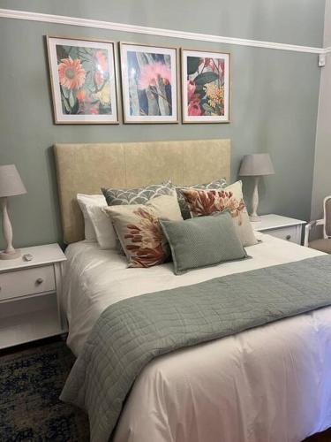 a bedroom with a bed with pillows and paintings on the wall at 7de Hemel Paarl in Paarl