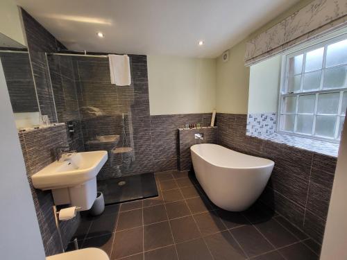 La salle de bains est pourvue d'une baignoire blanche et d'un lavabo. dans l'établissement The Manifold Inn Hotel, à Hartington