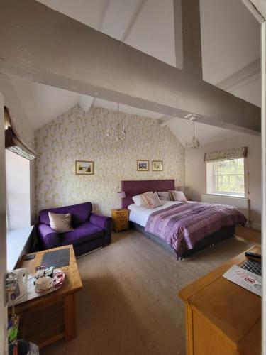 Un dormitorio con una cama grande y un sofá púrpura. en The Manifold Inn Hotel, en Hartington