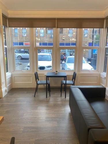 - un salon avec une table, des chaises et des fenêtres dans l'établissement Beautiful ground floor flat, à Londres