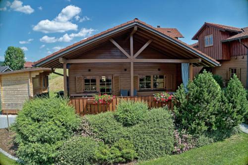 a home with a wooden house with bushes at Chalet Leithenwald in Zwiesel