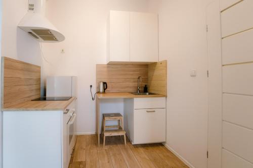 małą kuchnię z białymi szafkami i zlewem w obiekcie Cosy Balcony Apartment w Grudziądzu