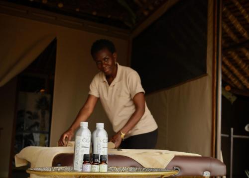 a man standing next to a table with bottles of wine at Soroi Larsens Camp in Buffalo Springs  National Reserve