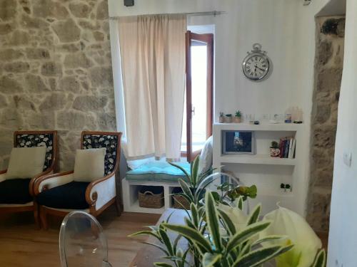 a living room with chairs and a clock on the wall at SARDEGNA DEL NORD - BELLISSIMA CASA CON TERRAZZA - INTERNET Wifi in Laerru