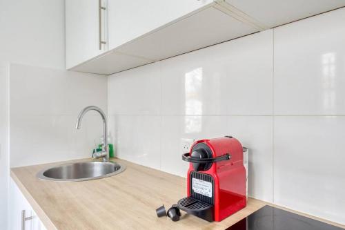ein rotes Gerät auf einer Küchentheke neben einer Spüle in der Unterkunft Cosy house in La Courneuve