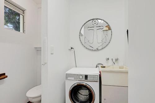 a bathroom with a washing machine and a clock on the wall at Frogmouth - 87 Mooloomba Road in Point Lookout