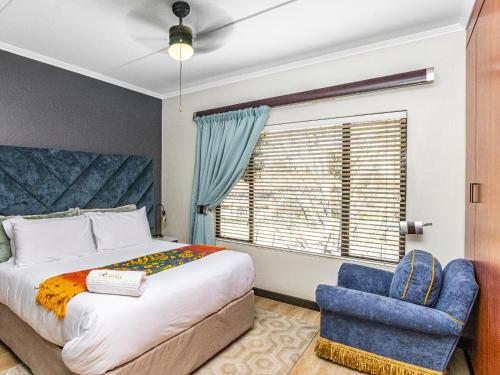 1 dormitorio con 1 cama y 1 silla azul en Sunninghill Spacious Executive Condo en Sandton