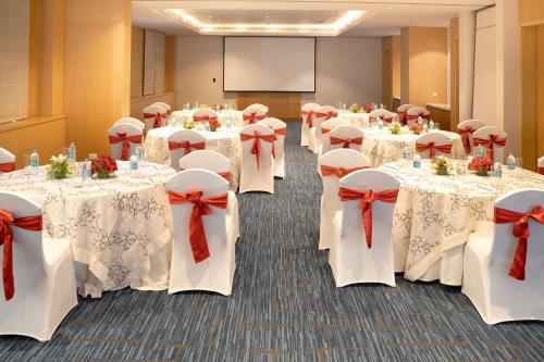 a row of tables with red bows in a room at Sheraton Hyderabad Hotel in Hyderabad