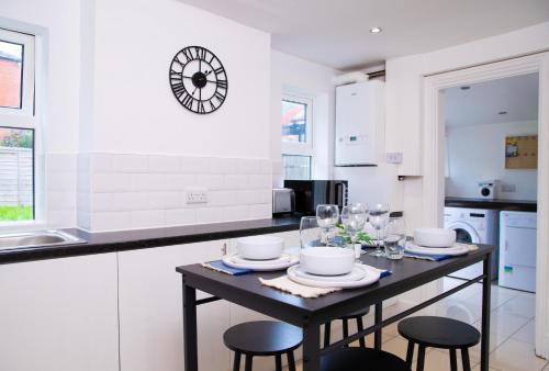 kuchnia ze stołem z krzesłami i zegarem na ścianie w obiekcie Comfortable Stay for 6, Charming 3-Bedrooms near Gloucester Quays with Parking w mieście Hempstead