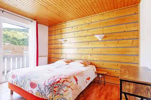 a bedroom with a wooden wall with a bed and a desk at Bargkass - Vue montagne et piscine in La Bresse