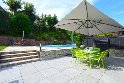 - une terrasse avec une table et un parasol à côté de la piscine dans l'établissement Bargkass - Vue montagne et piscine, à La Bresse
